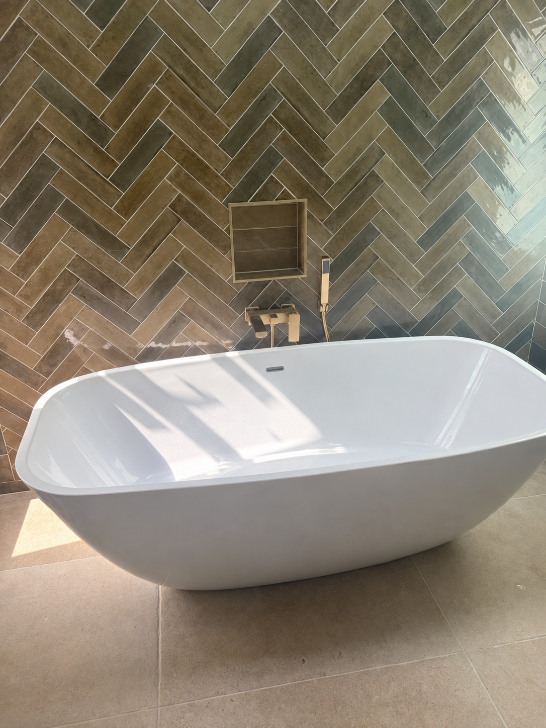 Freestanding bath with wall-mounted taps and herringbone tiled feature wall in Scone